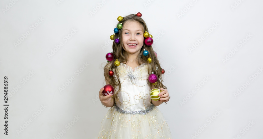 Girl with New Year's toys on a white background. A little girl with Christmas balls decorated hair on her head. Girl with New Year's toys on a white background. A little girl with Christmas balls decorated hair on her head.