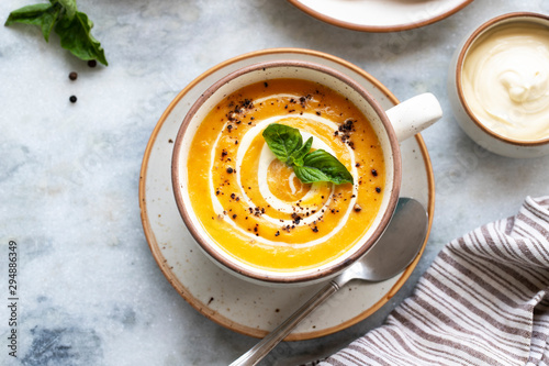 Yellow carrot or pumpkin soup with bread and sour cream on white marble background. Copy space. Homemade carrot soup puree and flatbread. Healthy eating. Halloween, thanksgiving. Top view. Flat lay.