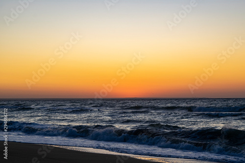 Sunrise over the Black sea  waves on the sandy beach.