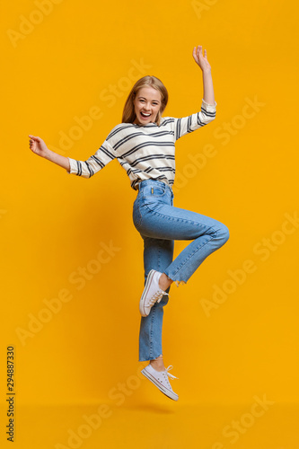Positive beautiful teen girl jumping in air with hands up