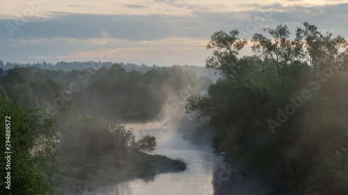 Morning fog over a small russian river in june during sunrise