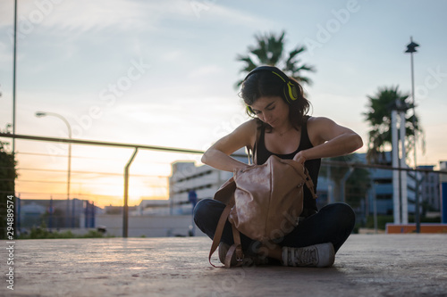 Young woman is searching something in her bag while she is listening music
