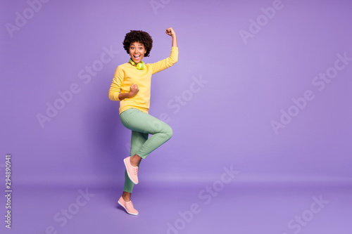 Fototapeta Naklejka Na Ścianę i Meble -  Full length body size photo of cheerful cute charming fascinating girl rejoicing found her favorite song she could not find for long wearing green pants trousers yellow sweater isolated violet pastel