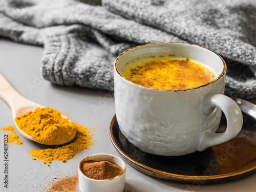 Turmeric latte with milk and cinnamon. Elixir of health and vivacity. Traditional healthy Indian detox drink. Grey background