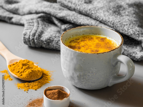 Turmeric latte with milk and cinnamon. Elixir of health and vivacity. Traditional healthy Indian detox drink. Grey background