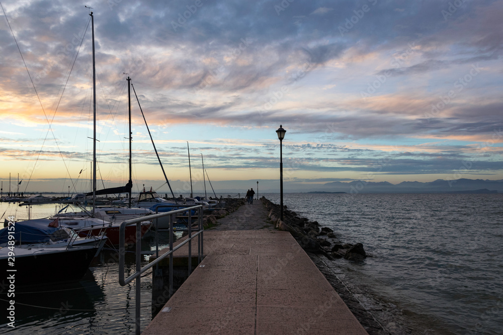 Pier at sunset on the lake Garda in Italy. Colorful sky and dramatic clouds