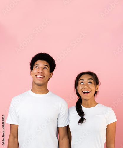 Excited teen guy and girl looking upwards at copy space