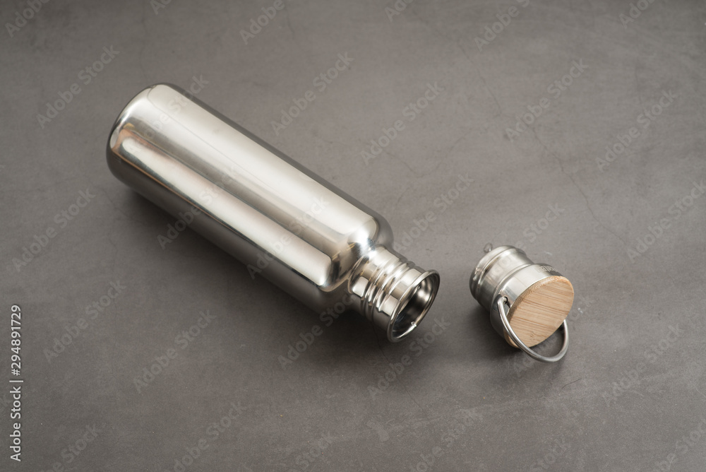 Naklejka premium Durable, high quality reusable stainless steel bottle on gray background as alternative to plastic bottles. Toxin, BPA, plastic free zero waste option for drinking tap water at home or at the office.