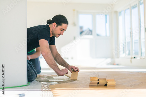 Carpenter on work putting wood parquet pieces. Home construction 