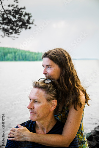 Woman embracing man and looking at lake photo