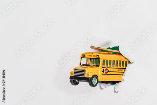 Back to school concept. school bus jumping through white paper