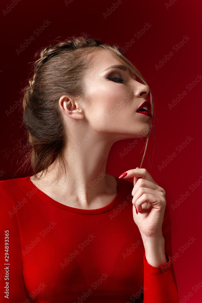 Obraz premium Portrait of sexy woman with fashion makeup and red lipstick on red background
