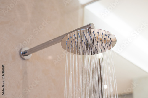 Shower turned on, overhead ceiling shower faucet head closeup. photo