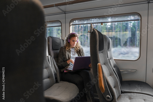 Young woman commuter on train using laptop