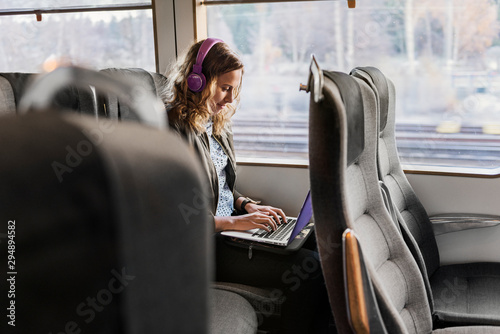 Young woman commuter on train using laptop