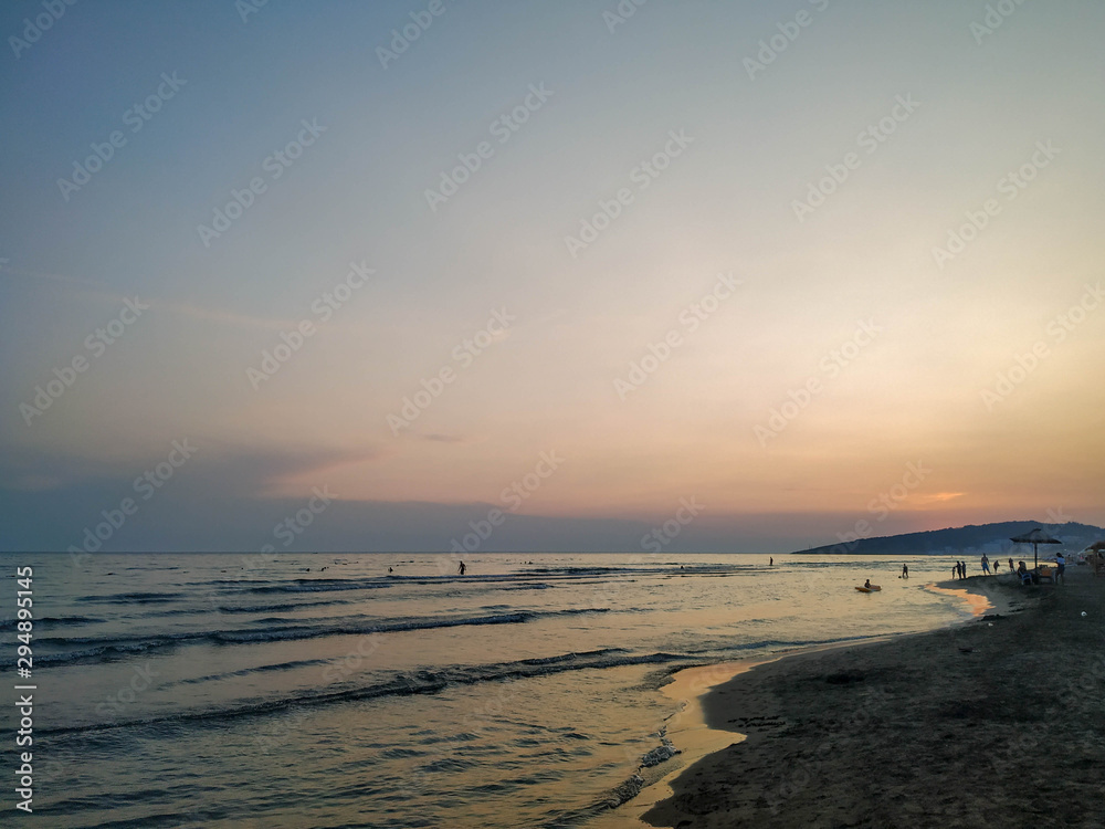 Colorful romantic sky during evening on a sandy beach with a view on wavy sea during sunset