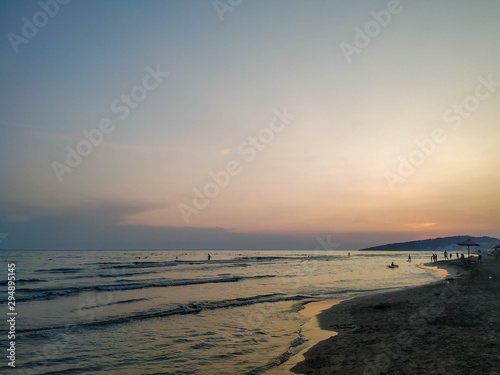 Colorful romantic sky during evening on a sandy beach with a view on wavy sea during sunset