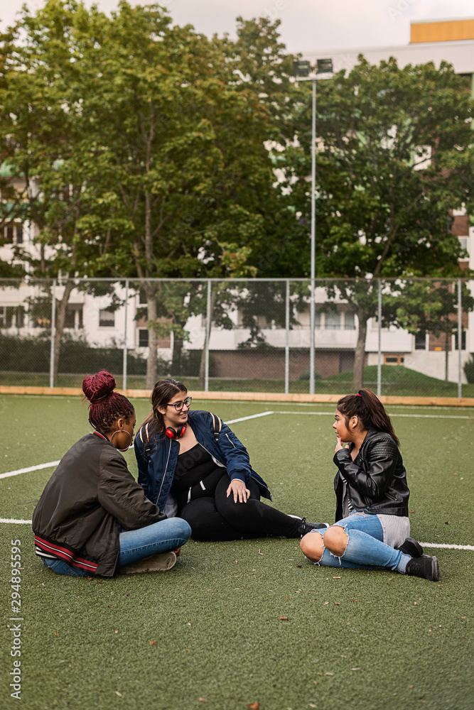 Teenage girls sitting on tennis court Teenage girls sitting on tennis court