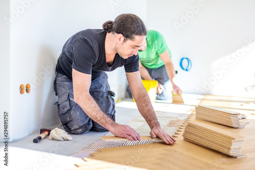 Carpenter on work putting wood parquet pieces. Home construction 