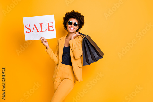 Portrait of positive cheerful afro american girl have sunglass free time on travel trip hold bags enjoy sales bargains want shop wear style fashionable outfit isolated over yellow color background