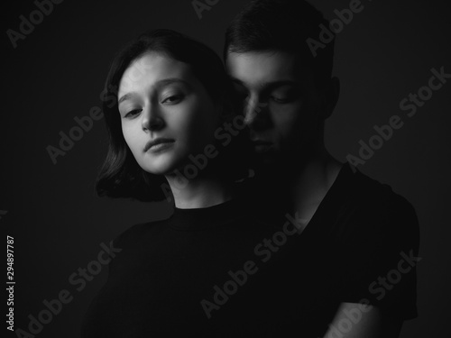 Handsome young man and girl posing in studio. Low key. Black and white