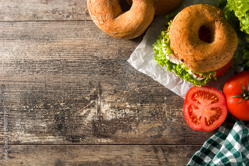 Bild auf Leinwand Vegetable bagel sandwich with tomato, lettuce, and mozzarella cheese on wooden table