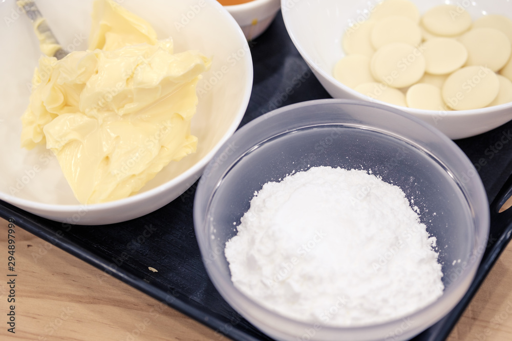 Sugar, butter, cream and white chocolate chips in a bowl for melting, preparing ingredients to make a cake. - obrazy, fototapety, plakaty 