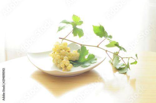 bunch of organic white grapes with its green leaves square plate backlight