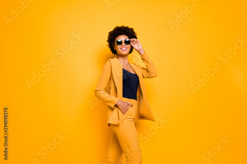 Portrait of positive dreamy magnificent dark skin lady enjoy time on fall holidays touch spectacles wear style clothes isolated over yellow bright color background