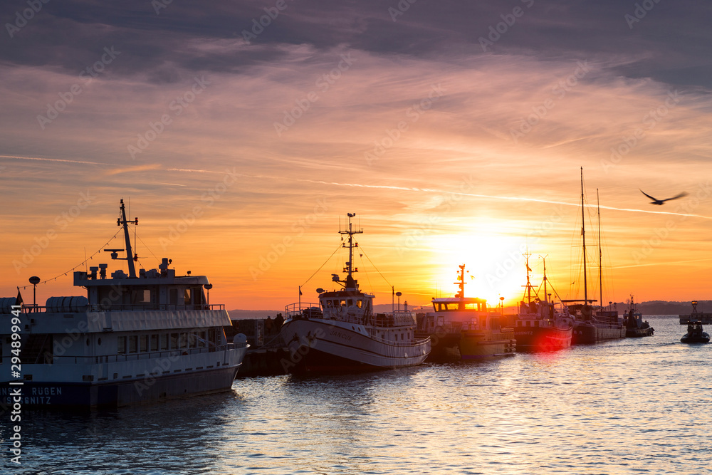 Fototapeta premium Fishing boats in harbor of Sassnitz at ruegen island. The sun sets in the background, Sassnitz, Ruegen Island