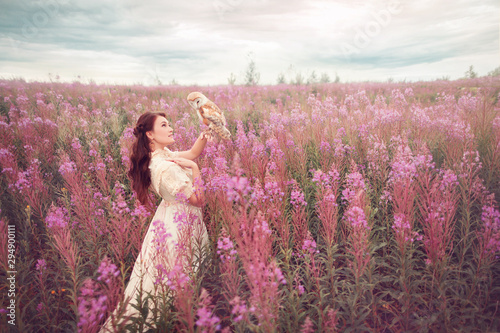Vintage woman looking to her owl at field of pink flowers.