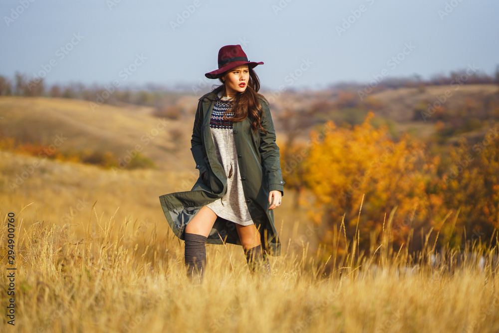 Beautiful young stylish girl in a coat walks in the autumn in the park. The girl is dressed in a green coat and a red hat. Beautiful evening. Autumn fashion. Lifestyle. High fashion portrait. Beautiful young stylish girl in a coat walks in the autumn in the park. The girl is dressed in a green coat and a red hat. Beautiful evening. Autumn fashion. Lifestyle. High fashion portrait.