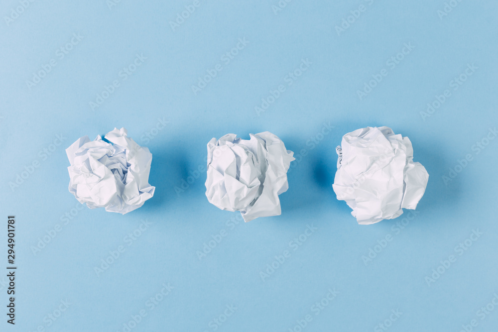 Crumpled paper balls, waste and recycling concept on blue background