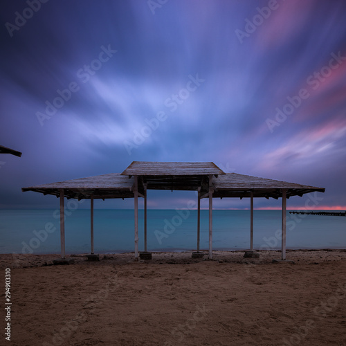 Long exposure sea wooden canopy on the beach at sunset
