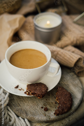 Cup of coffe with milk and chocolate cookies on warm wool blanket