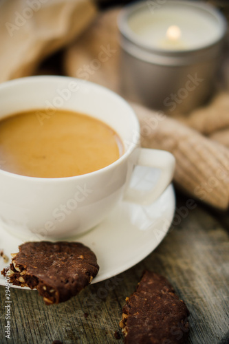 Cup of coffe with milk and chocolate cookies on warm wool blanket