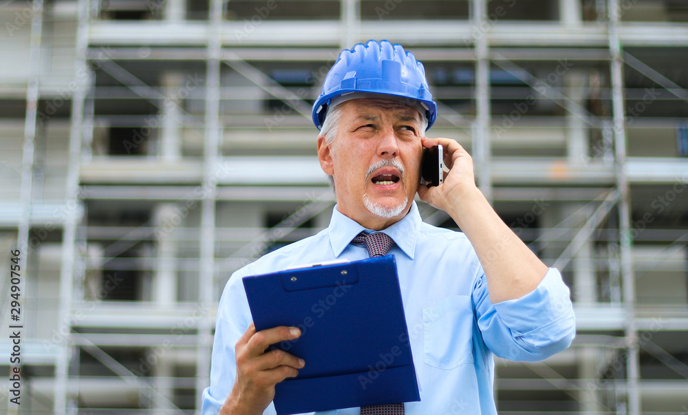 Engineer builder at construction site talking on the phone Engineer builder at construction site talking on the phone