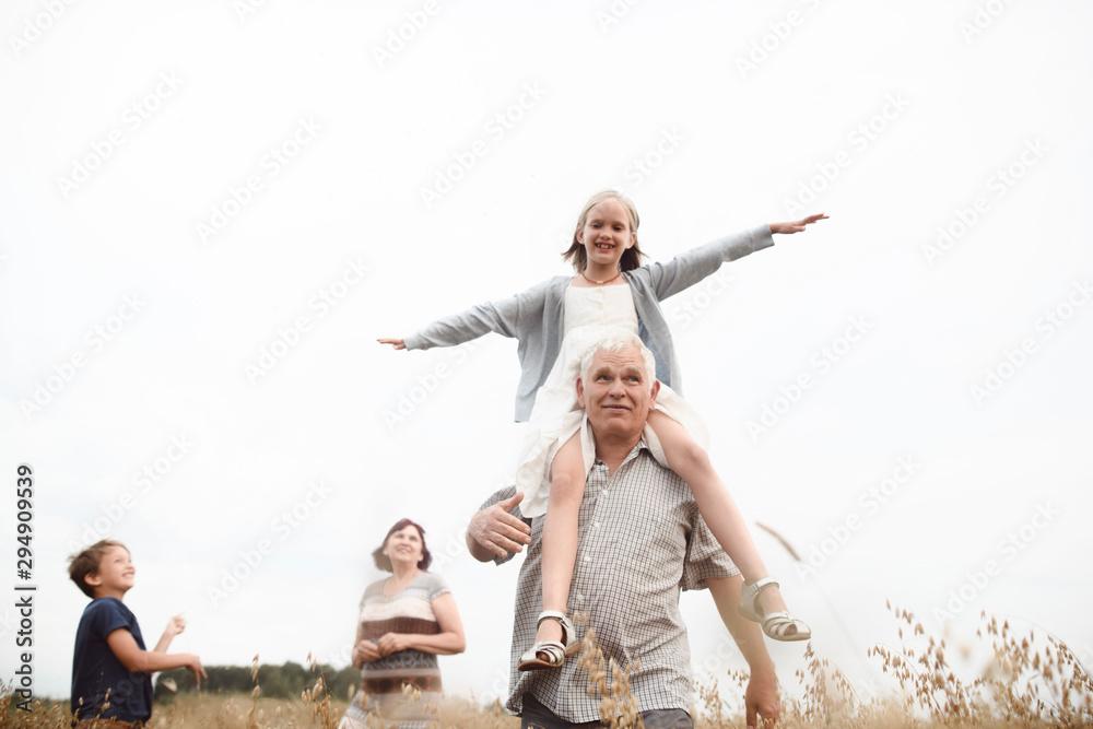 Happy Girl Sitting On Her Grandfather s Shoulders In Nature With happy-girl-sitting-on-her-grandfather-s-shoulders-in-nature-with