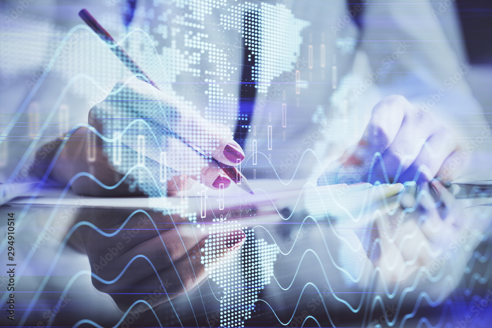 A woman hands writing information about stock market in notepad. Forex chart holograms in front. Concept of research. A woman hands writing information about stock market in notepad. Forex chart holograms in front. Concept of research.