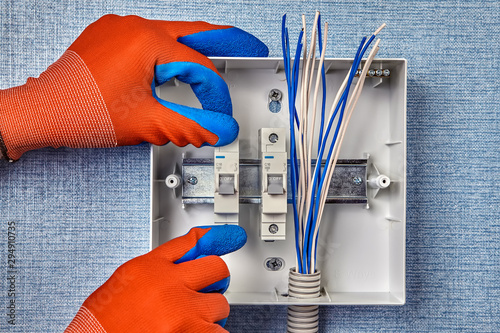 A handyman installs the fuse box in home wiring. photo