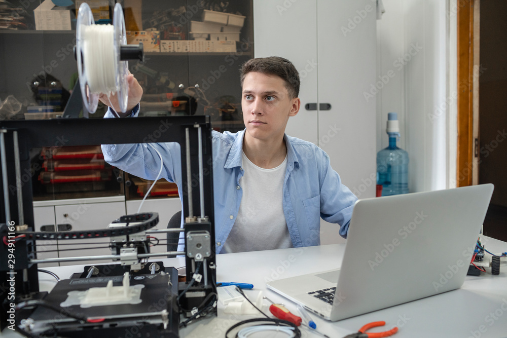 Student setting up 3D printer, using laptop Student setting up 3D printer, using laptop
