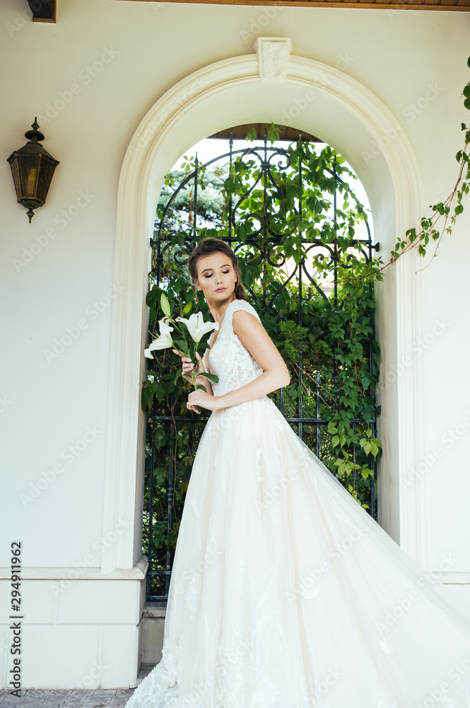 Fototapeta premium Beautiful bride with wedding flowers bouquet, attractive woman in wedding dress. Happy newlywed woman. Bride with wedding makeup and hairstyle. Smiling bride. Wedding day. Gorgeous bride. Marriage.