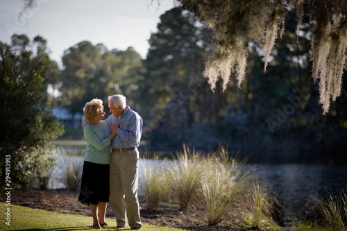 Happy senior couple walking close together near a lake.