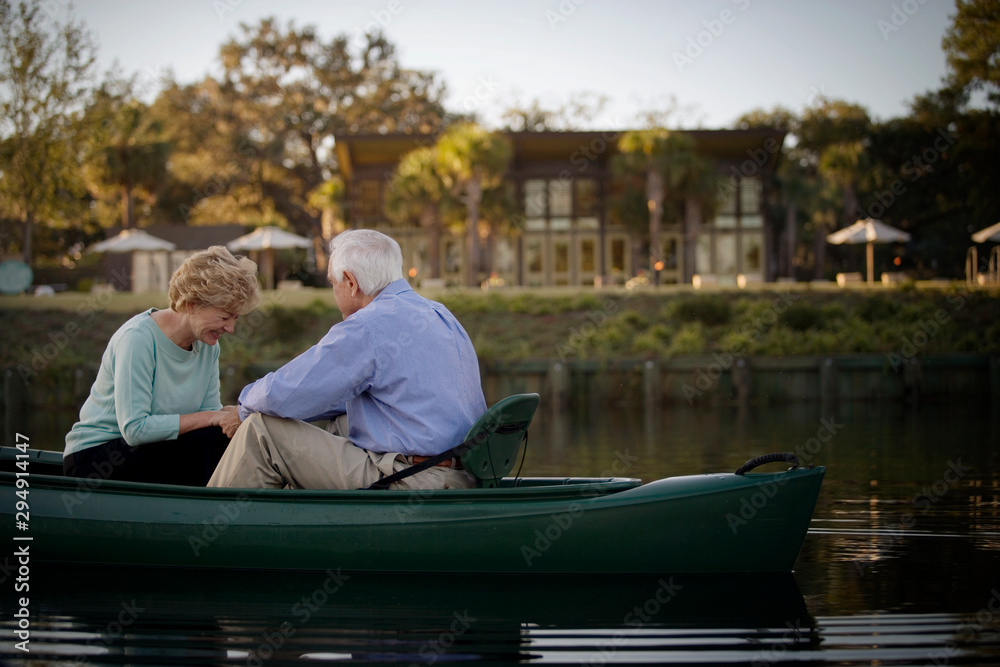 Happy senior couple holding hands while in a canoe.