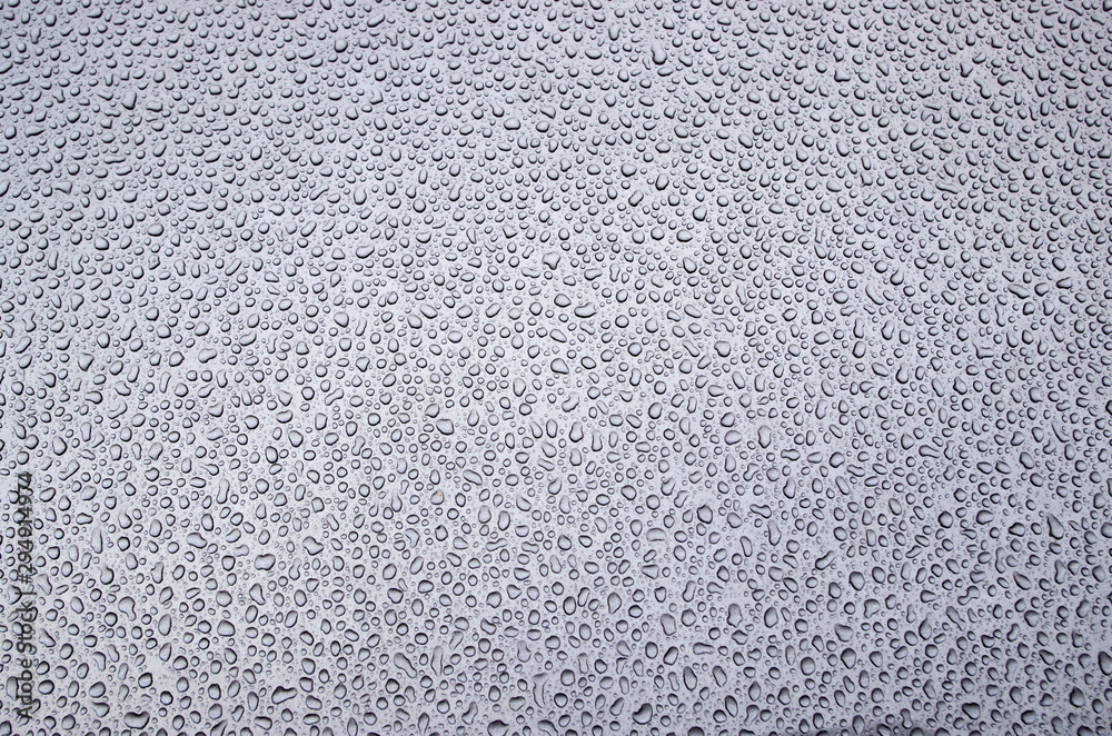 Morning pattern of chaotically arranged drops of water passed the day before rain or dew on the metal front hood of a bluish gray car. Morning pattern of chaotically arranged drops of water passed the day before rain or dew on the metal front hood of a bluish gray car.