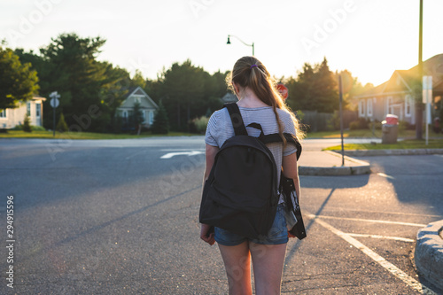 Tableau sur toile Teen girl depressed/sad at sunset in a parking lot while wearing a backpack and holding binders