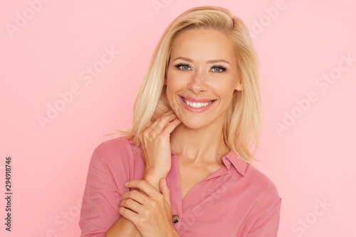 Delicate blonde woman looking pretty in pink shirt.