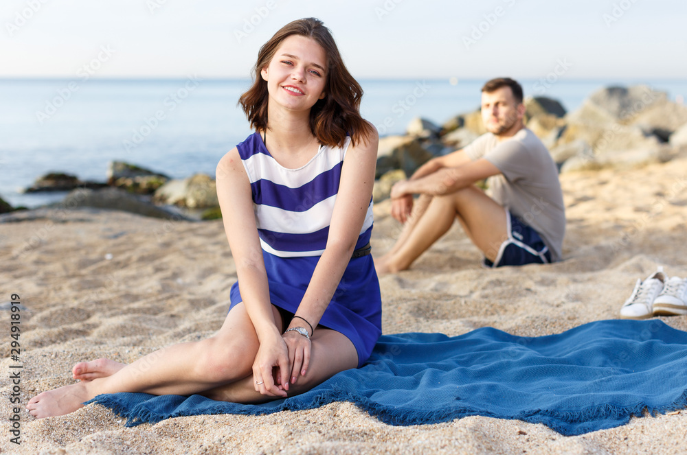 Fototapeta premium Girl sitting on the beach. Man on the background