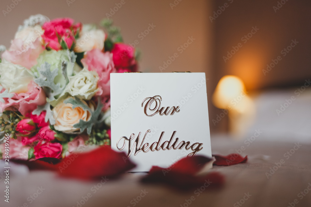 Obraz premium Box with the inscription our wedding lies on the bed with a bouquet of brides