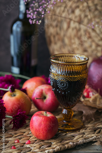 Glass of red wine, apples, grapefruits, autumn leaves and flowers